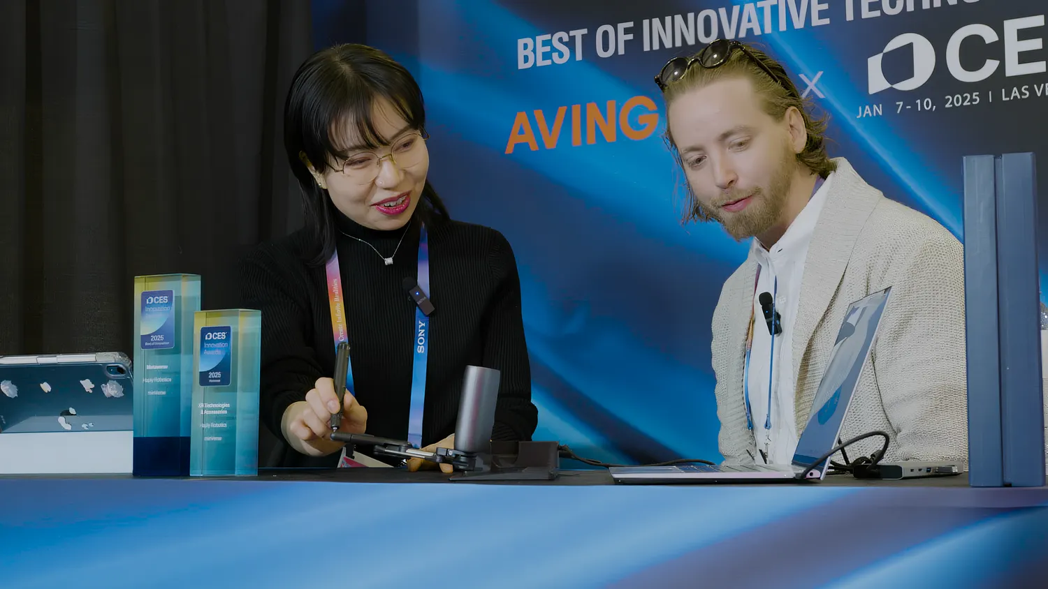 Visitors trying the MinVerse at Haply's CES booth, beside two CES Innovation Award trophies